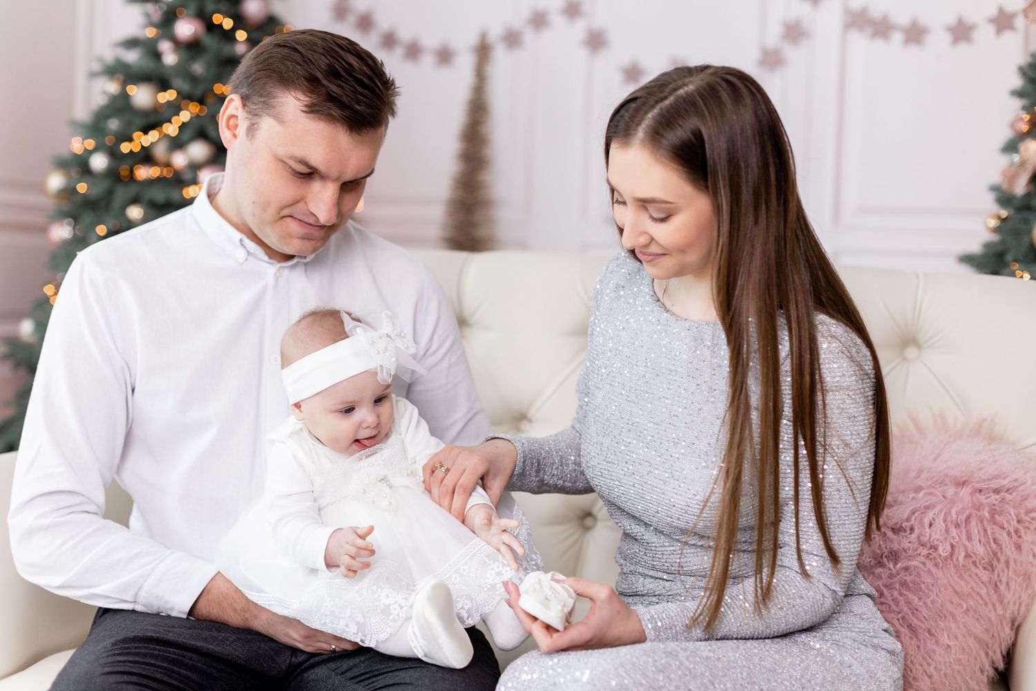 Family sitting together on white couch during Christmas photo session.