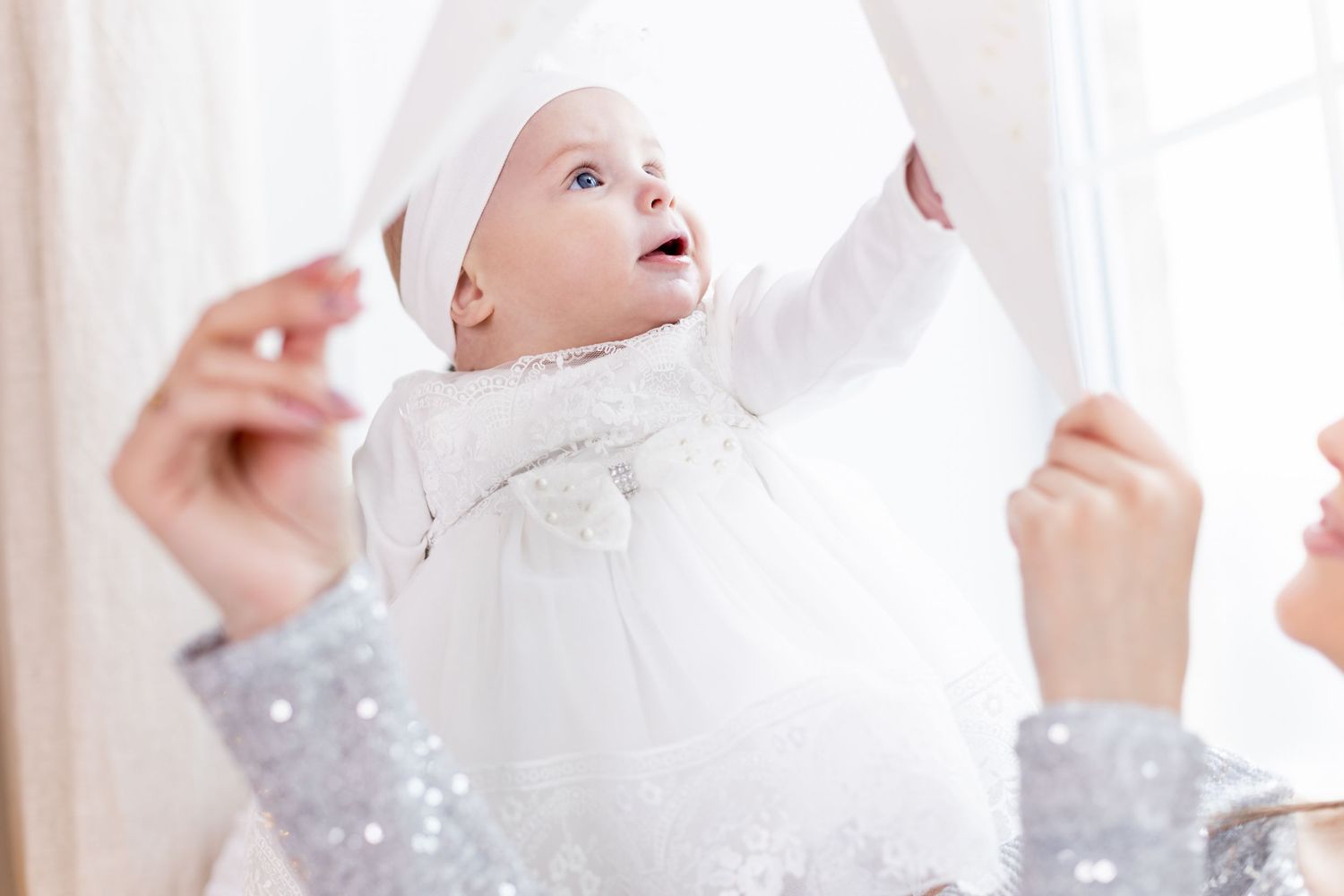 Sweet baby in white outfit during Christmas photo session with sparkly background.
