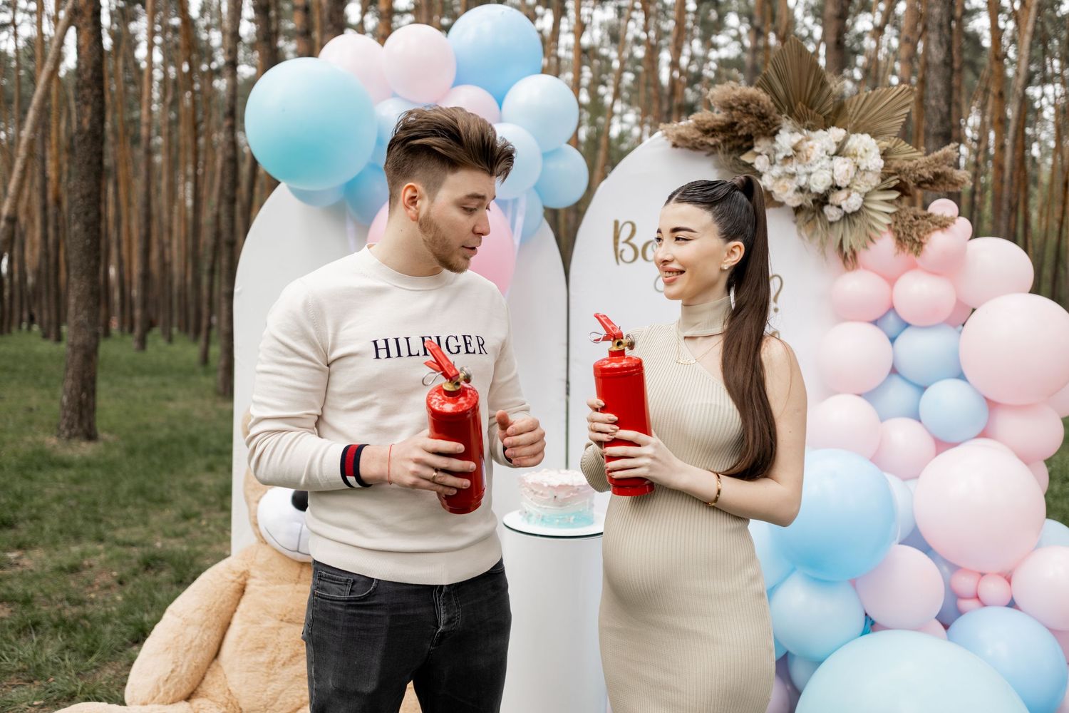 Forest gender reveal party scene with balloon decorations and refreshments.