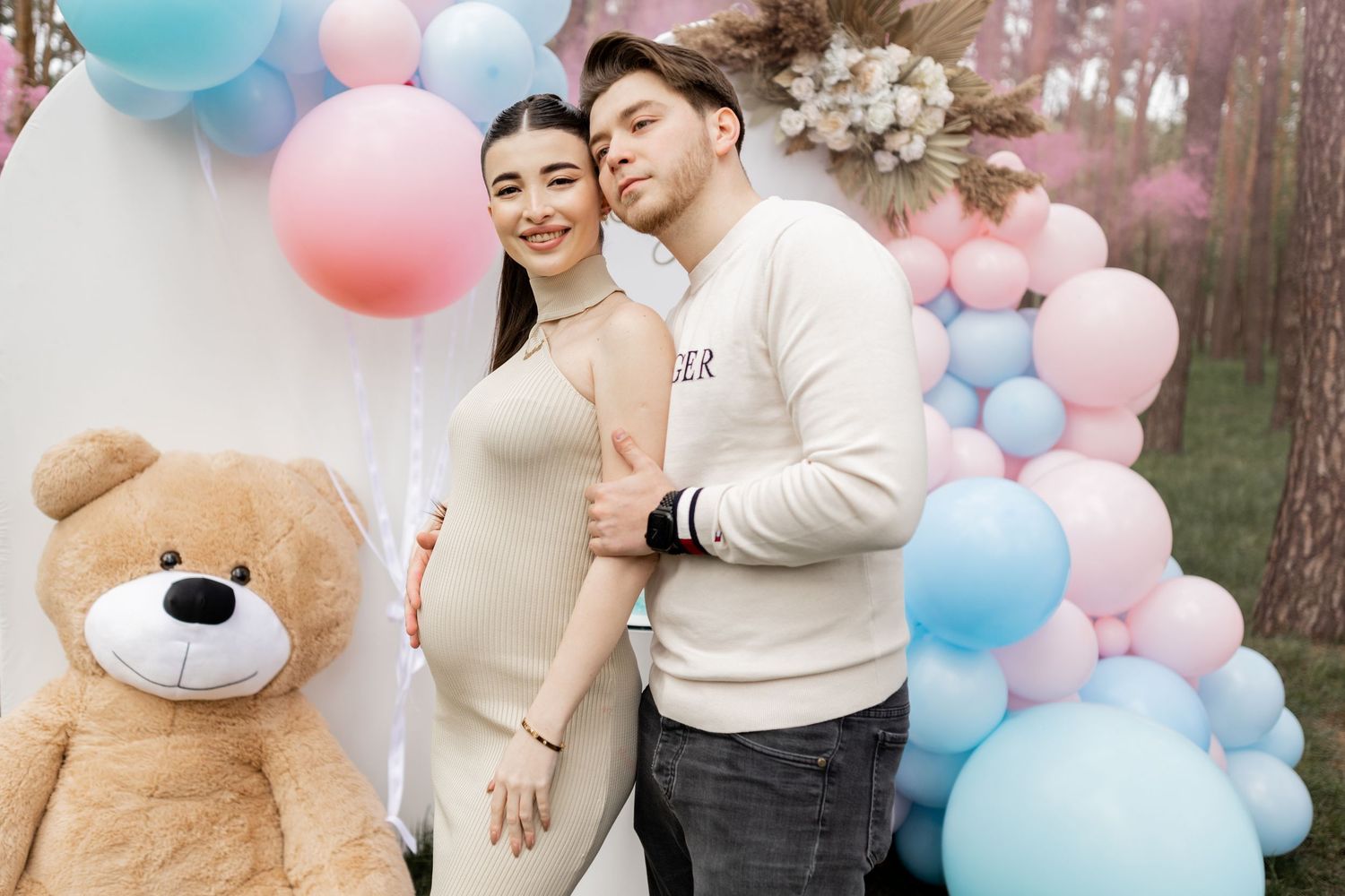 Forest gender reveal party setup with pink and blue balloon decorations.