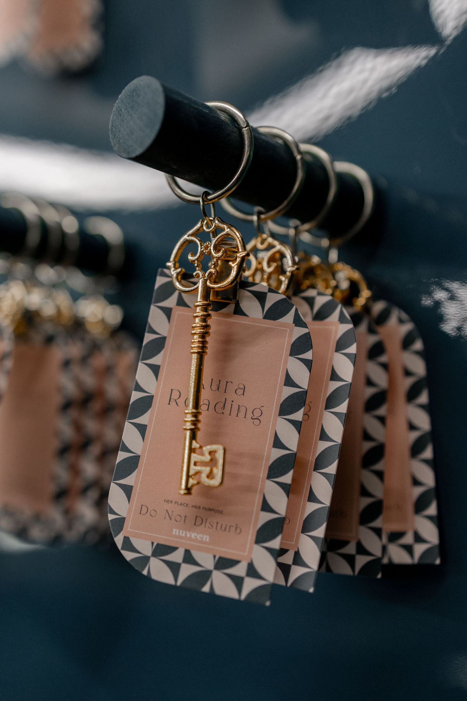 Decorative gold skeleton key keychains with geometric patterned hotel room tags hanging on a rack.