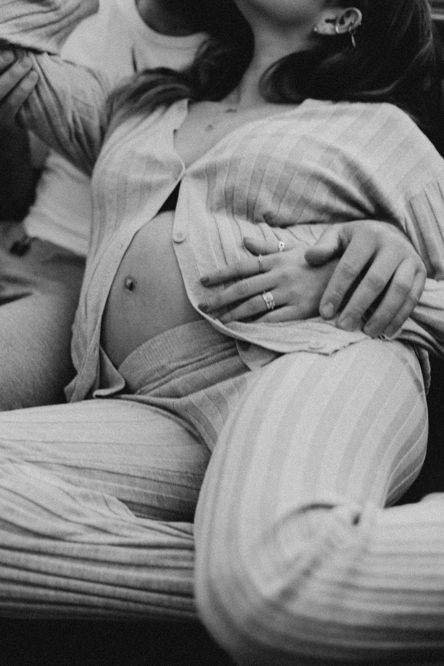 Black and white image of hands gently resting on a striped fabric in a tender moment.