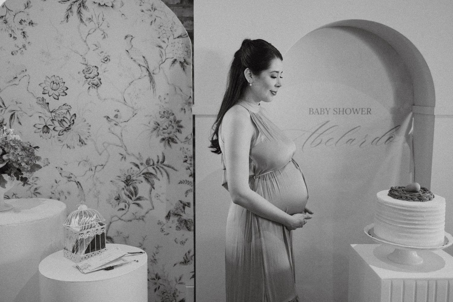 Black and white maternity photos showing tender moments against floral wallpaper.