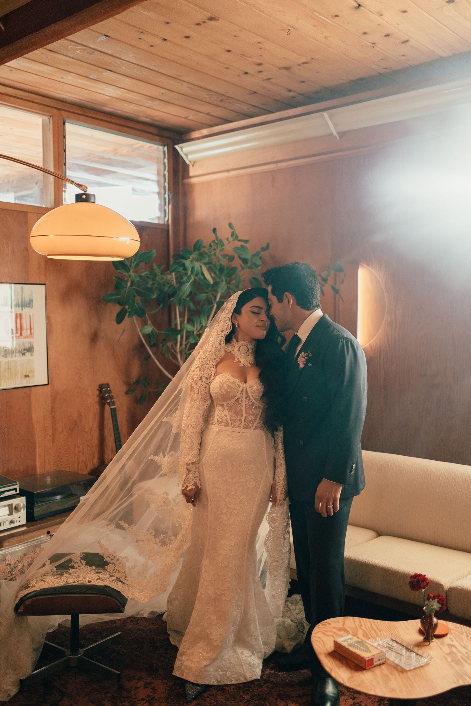 A romantic wedding moment captured in a room with wood paneled ceiling and warm lighting.