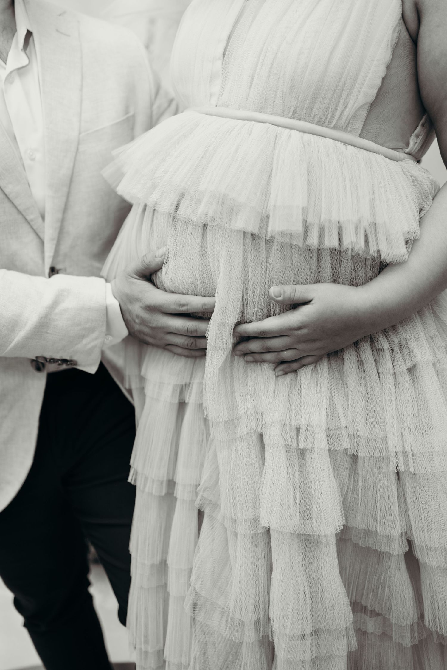 Series of images showing a white ruffled maternity dress against a dark background.