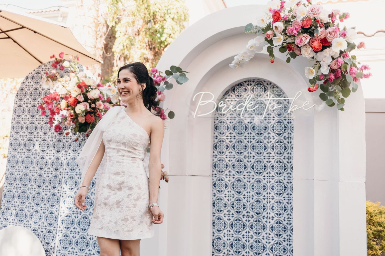 Wedding venue decorated with pink floral arrangements against white arches with blue tile details.