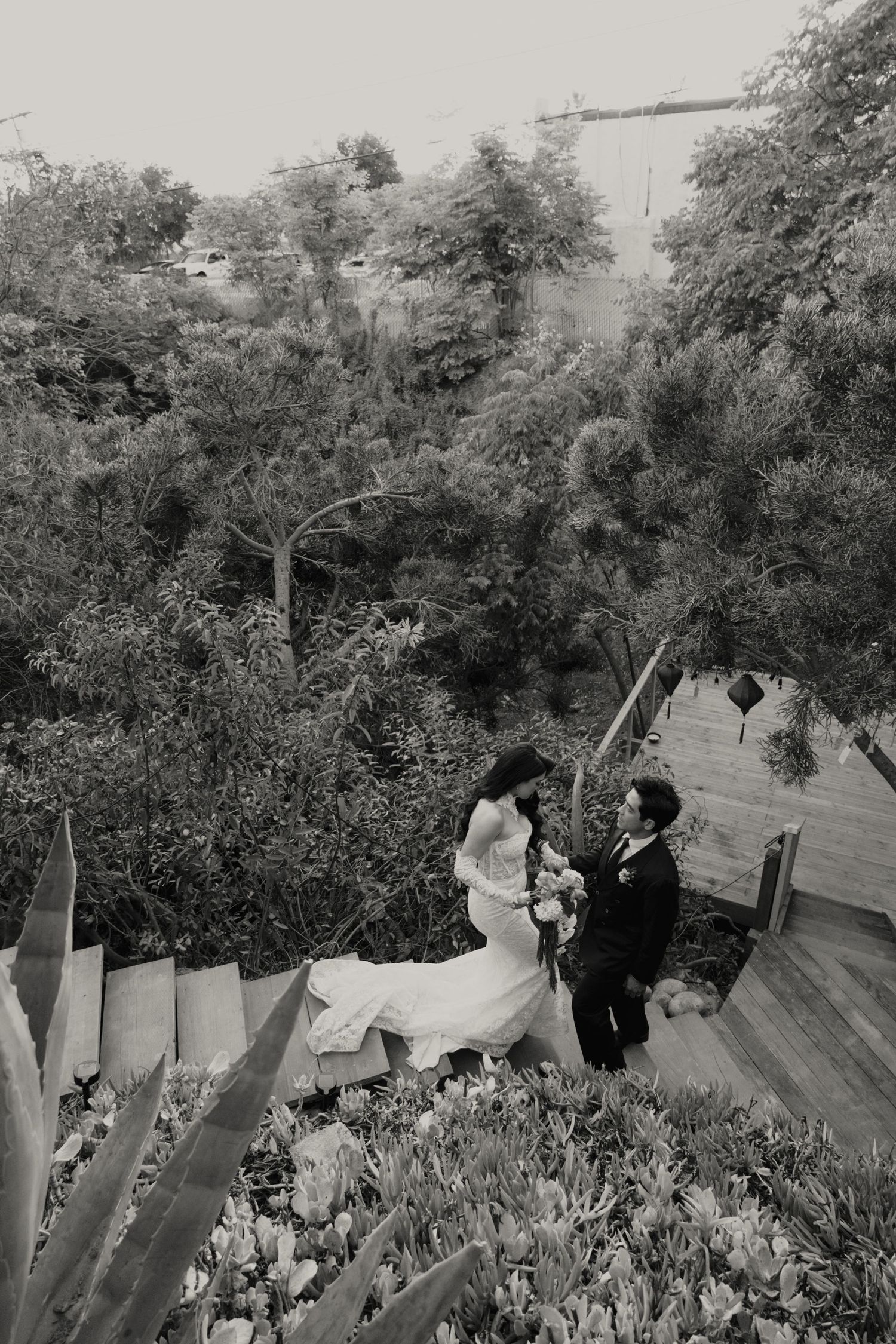 A vintage black and white panoramic photograph shows people gathered in a garden setting with trees in the background.
