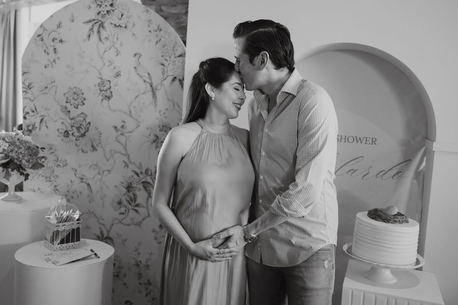 Romantic maternity photoshoot featuring intimate moments against floral wallpaper.