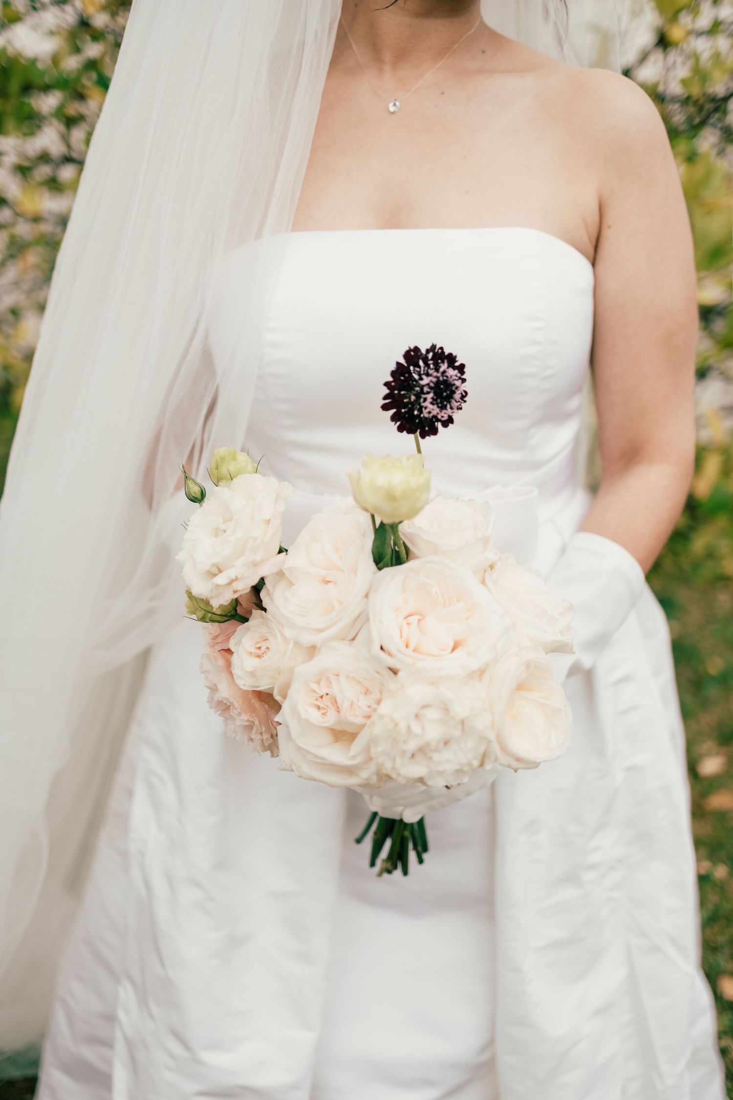 Close-up view of a bridal bouquet with soft peach roses against a white wedding dress.