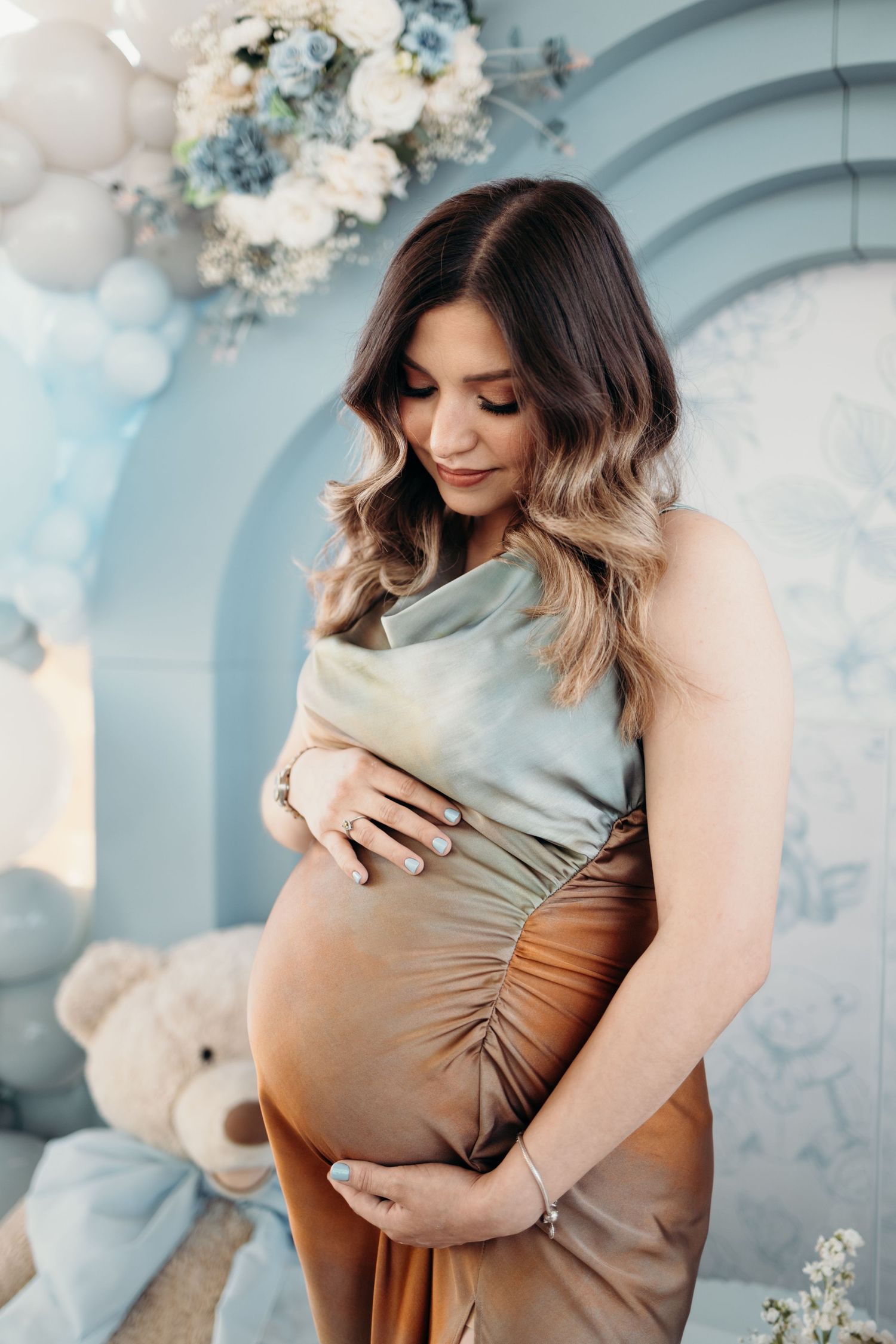 Maternity photos with blue and white floral decorations against a light blue backdrop.