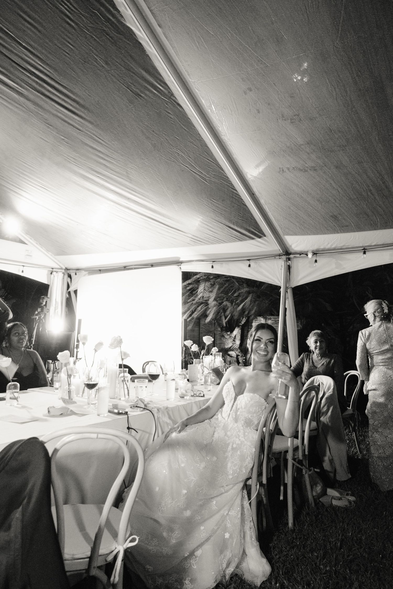 Black and white photos show a wedding reception under a tent with tables, guests, and party decorations.