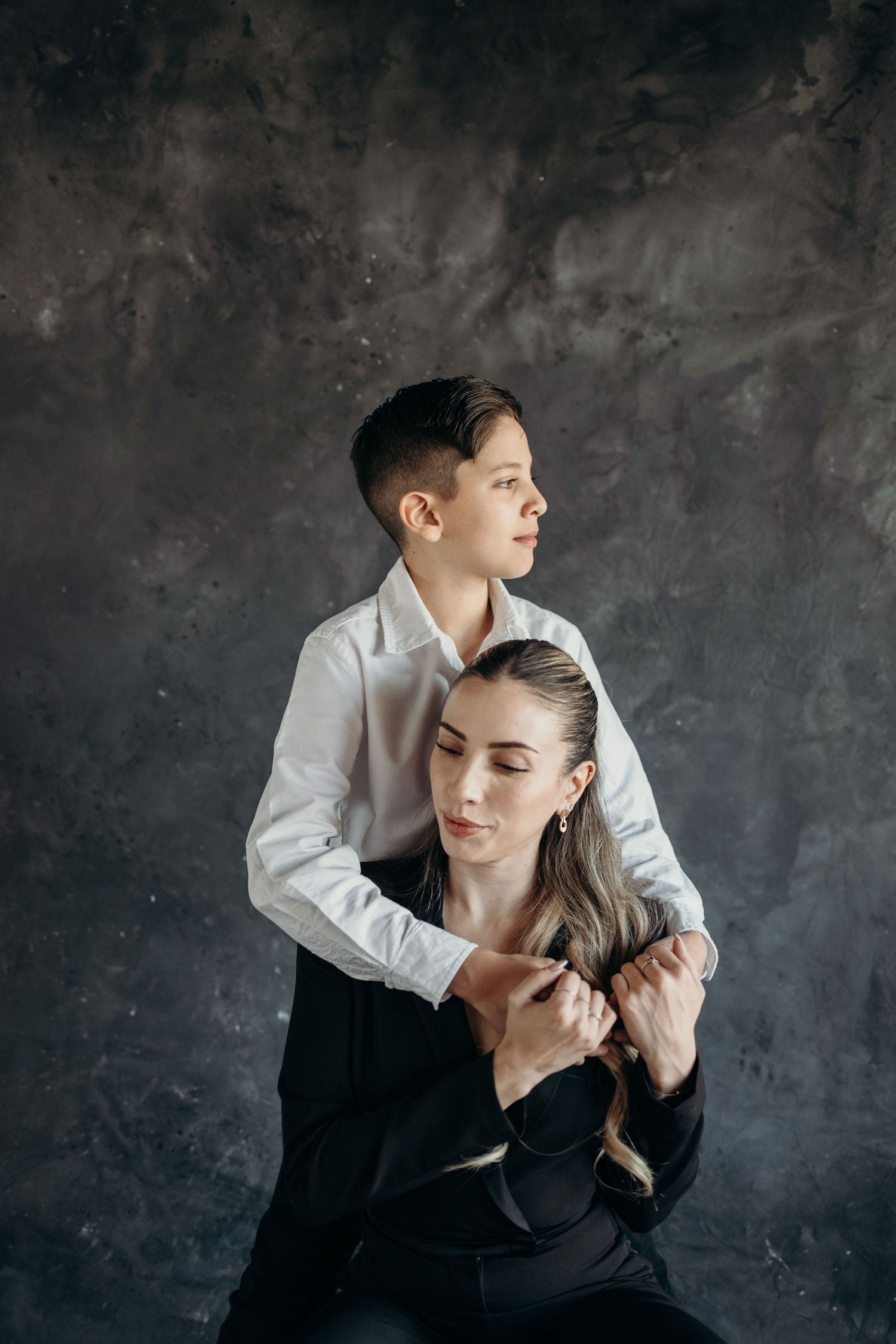 A couple in black and white attire dance together expressively against a dark textured background.