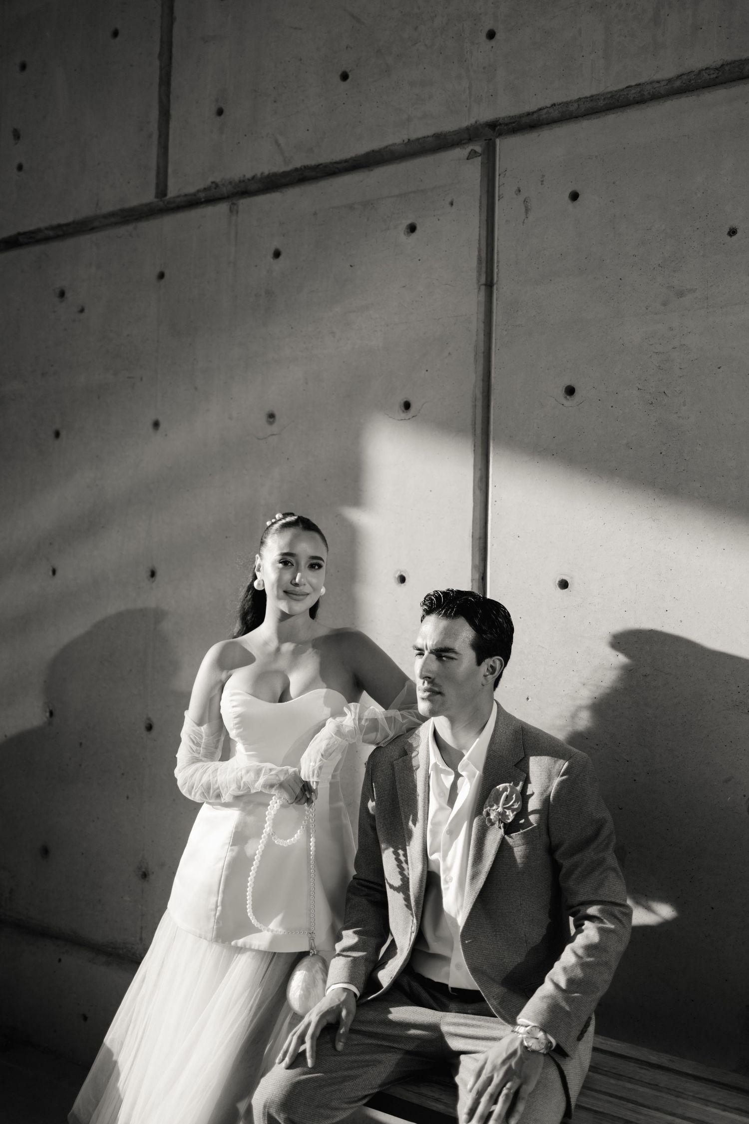 A dramatic black and white photo sequence showing a couple in wedding attire casting shadows on a concrete wall.