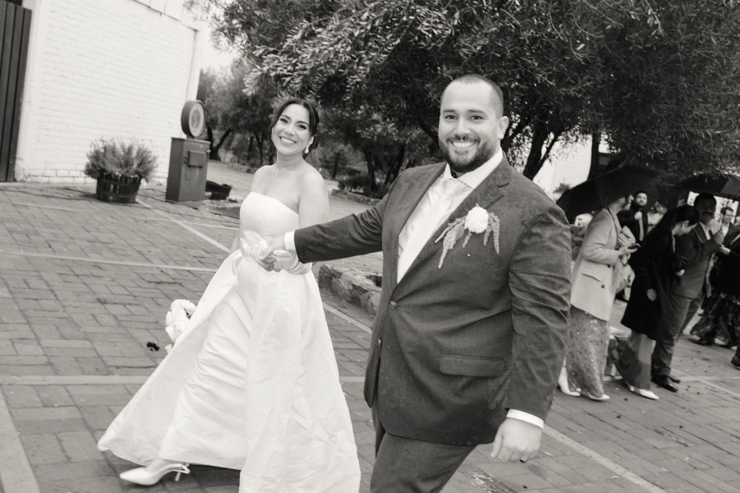 A couple in formal wedding attire dance together during their celebration on an outdoor patio.