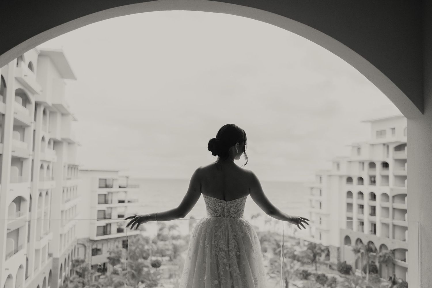Black and white photo of a silhouetted figure in a wedding dress framed by an archway.