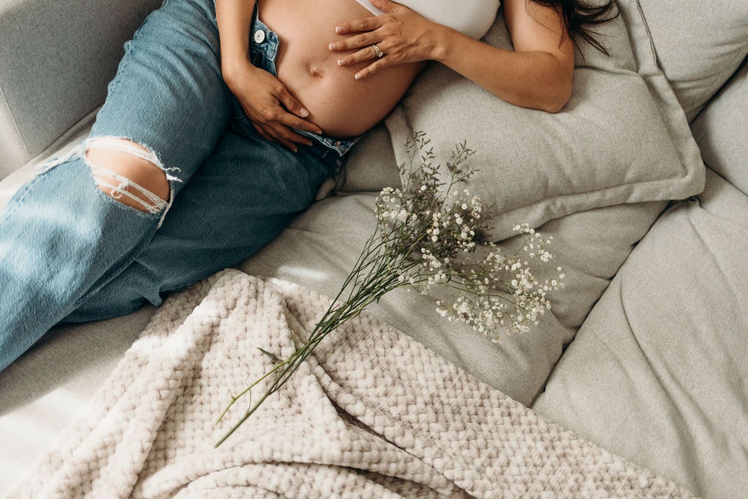 Intimate lifestyle photos on a gray couch with soft textiles and baby's breath flowers.