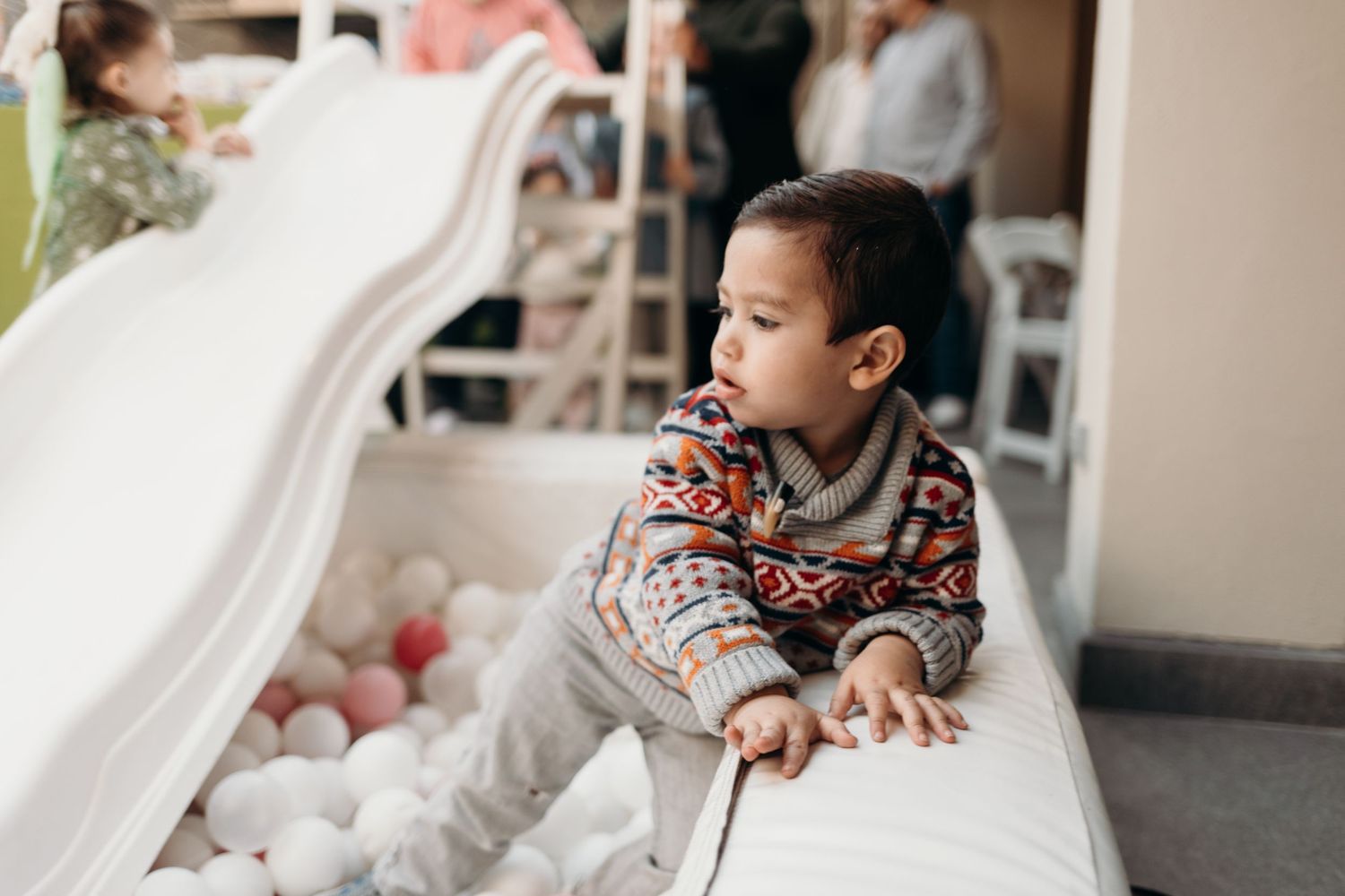 A child plays in a white ball pit at an outdoor celebration.