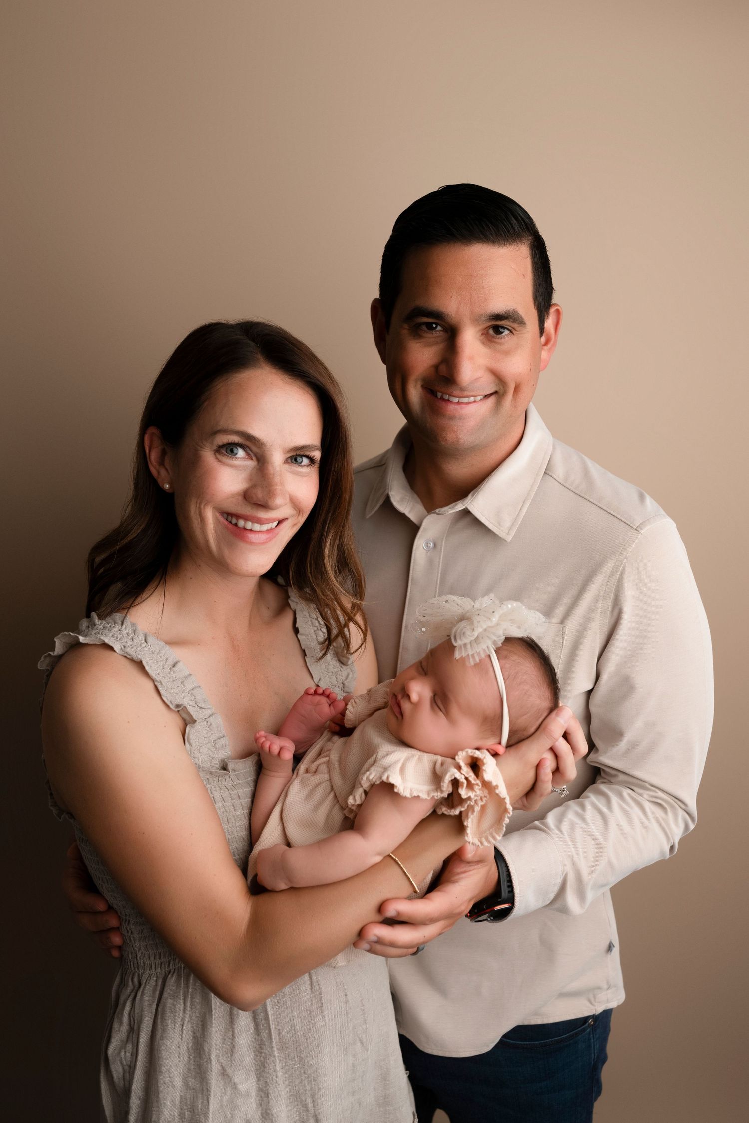 A series of warm-toned studio portraits showing tender family moments with a newborn baby in neutral colors.