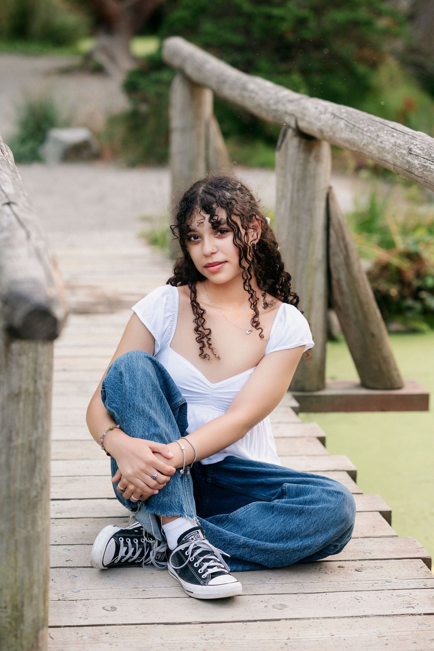 A person in casual attire sits on a wooden deck wearing jeans and sneakers, captured in multiple poses.