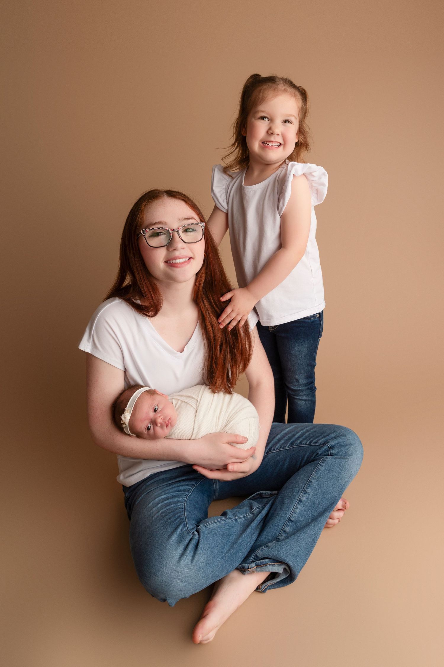 Natural lifestyle family photography session featuring tender moments on neutral backdrop.