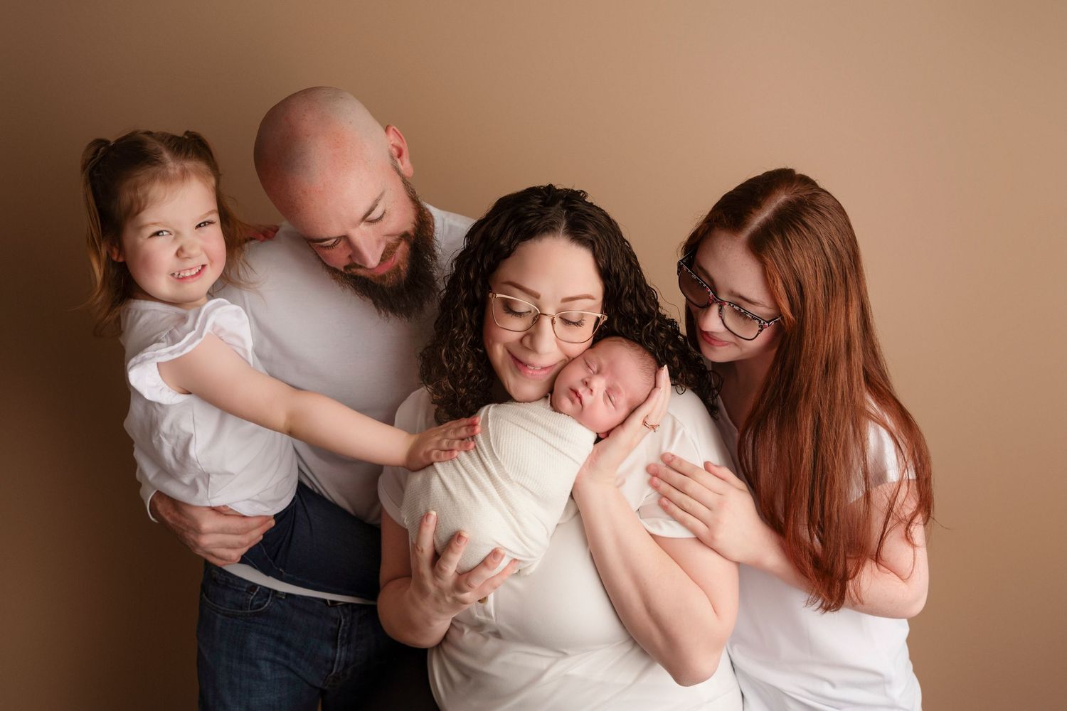 A group poses together in warm neutral tones wearing white and beige clothing for an intimate portrait session.