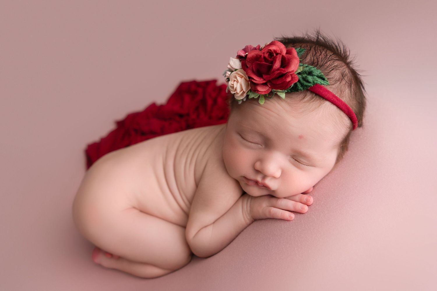 Artistic newborn photography collage featuring six peaceful sleeping poses with red floral accents on pink backgrounds.