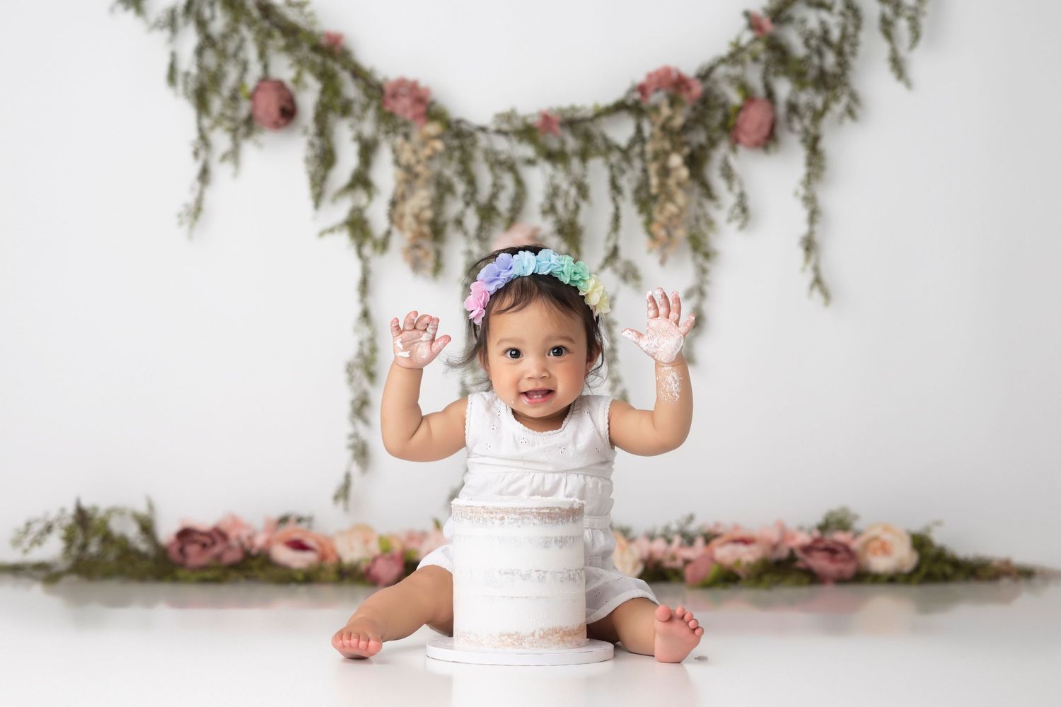 A baby in a white dress sits on the floor against a floral backdrop in a photo collage.