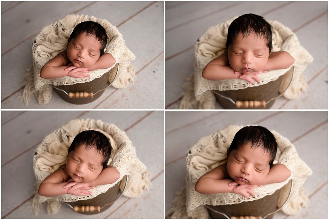 Newborn photography session showing sleeping baby in round wooden bowl with pink cushioning and cream backdrop.