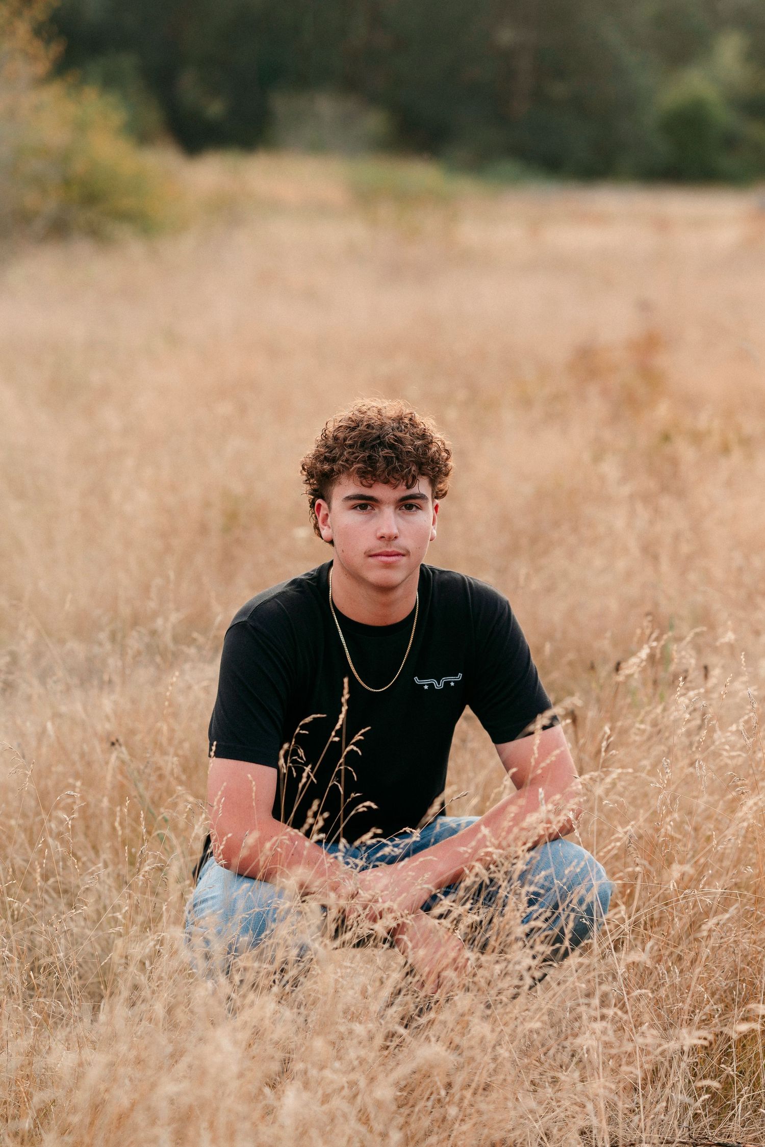 Relaxed pose in dry autumn grass field during golden hour photography session.