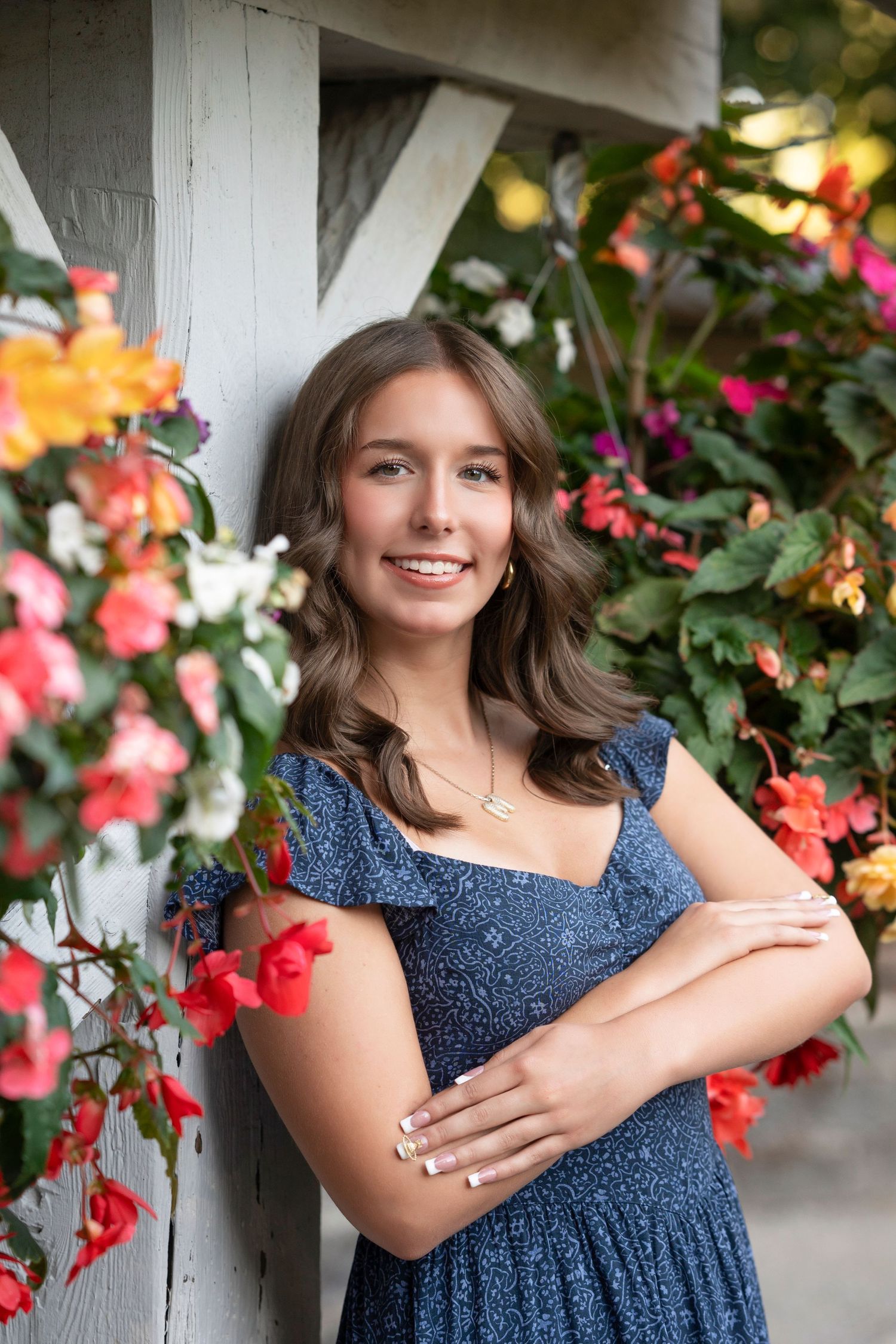 A series of outdoor portrait photos with blue dress against a backdrop of vibrant red flowers and greenery.