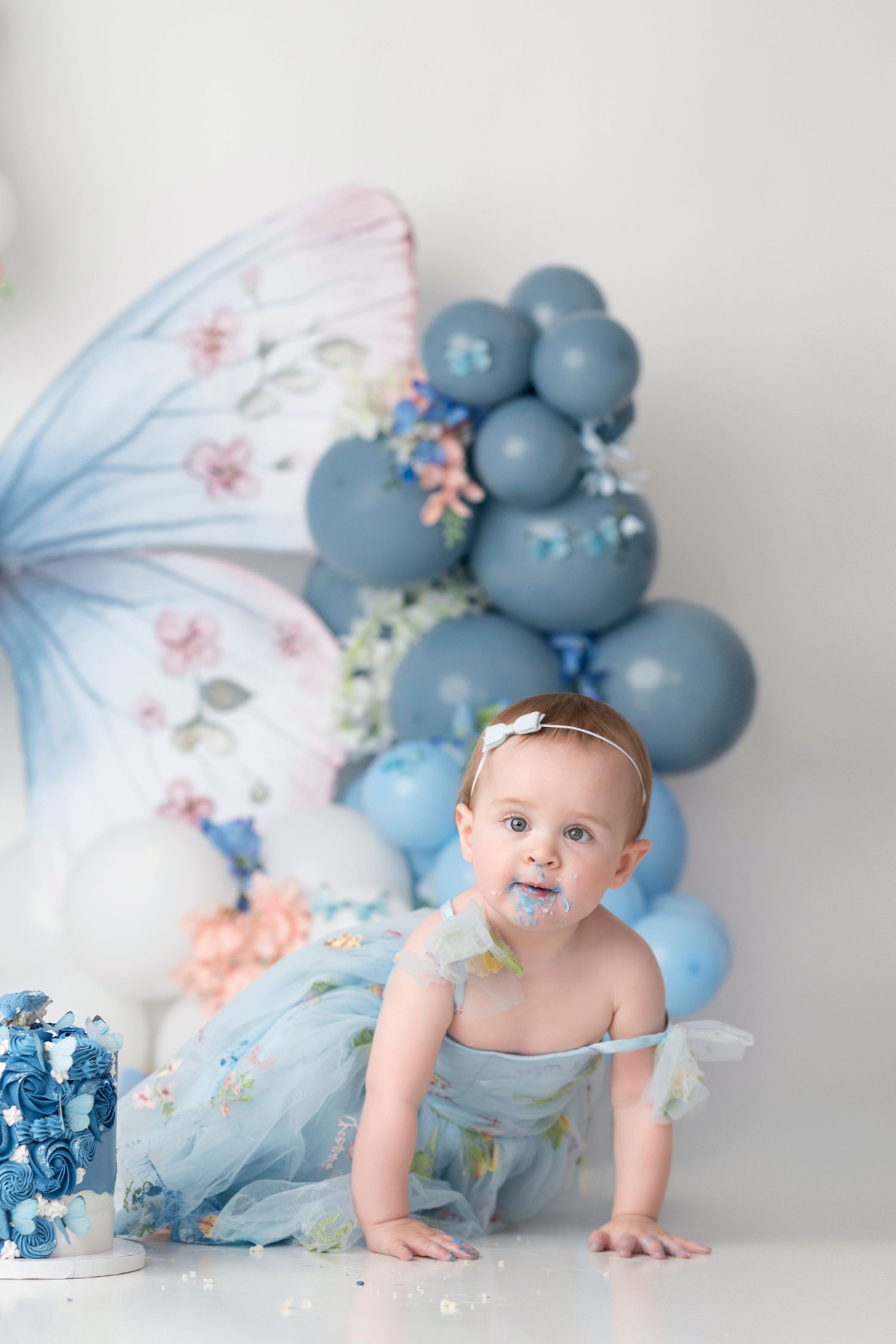 A decorated set with blue balloons, butterflies and floral elements creates a dreamy photography backdrop.