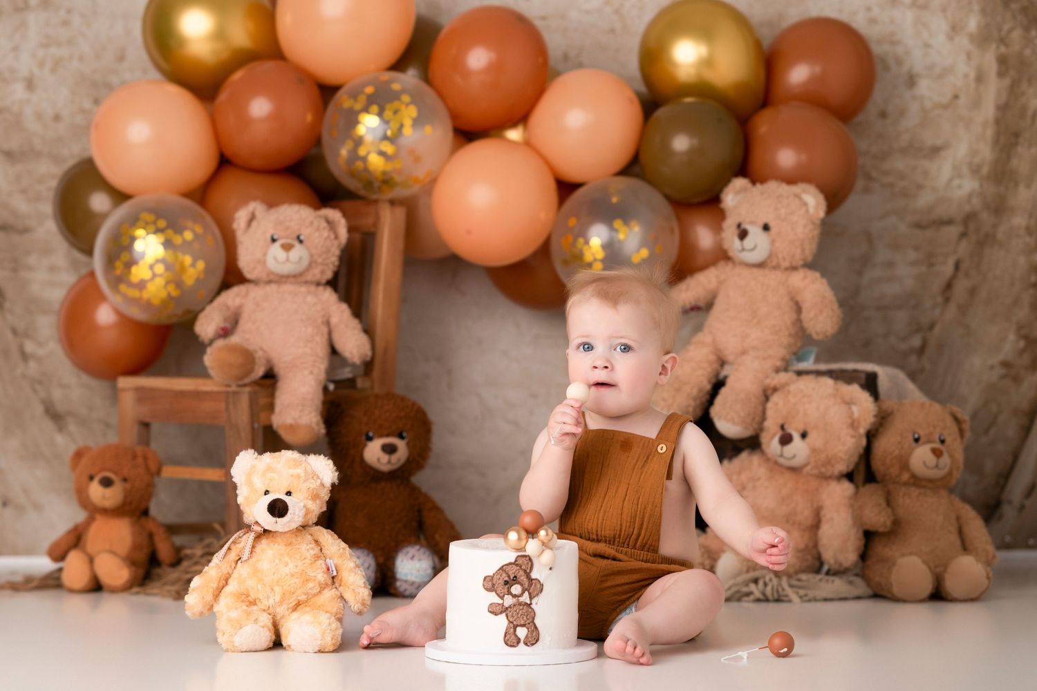 Baby's first birthday cake smash with teddy bears and brown balloon garland backdrop.