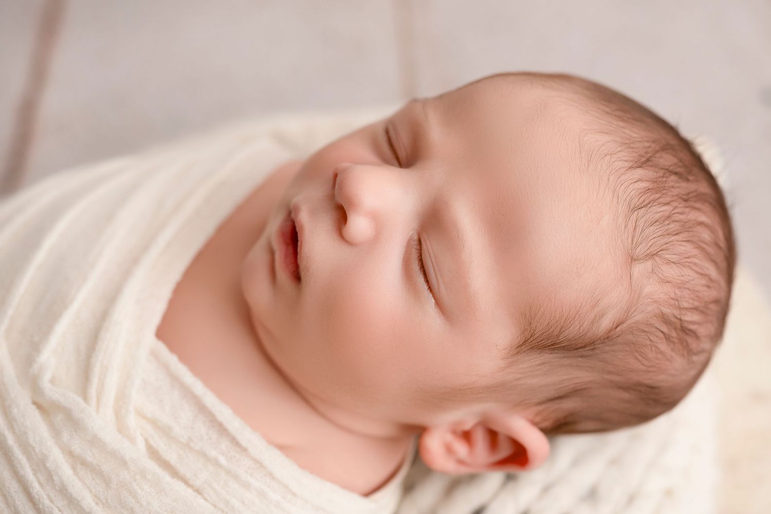 A sleeping newborn baby lies peacefully on soft white bedding in a series of connected photos.