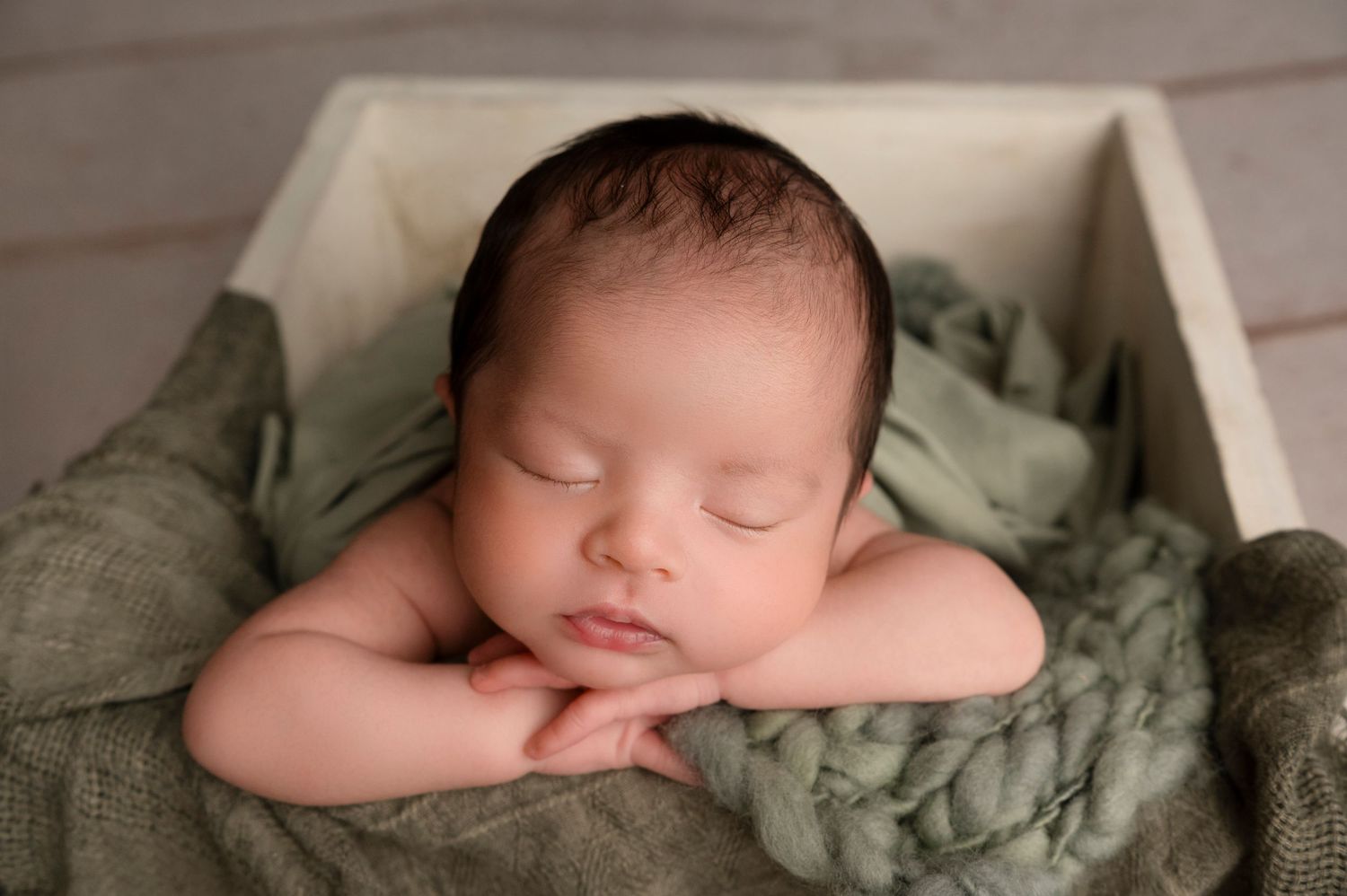 A series of peaceful newborn baby photos showing gentle poses on soft green fabric.