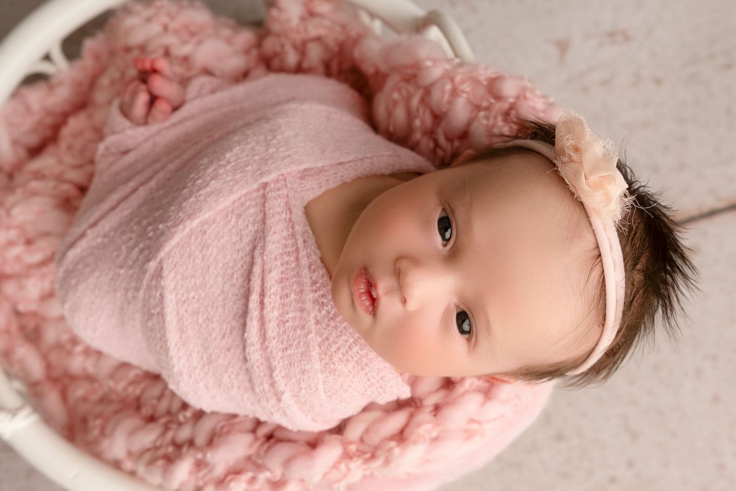 A baby wearing pink clothing lies on a white blanket in various poses.
