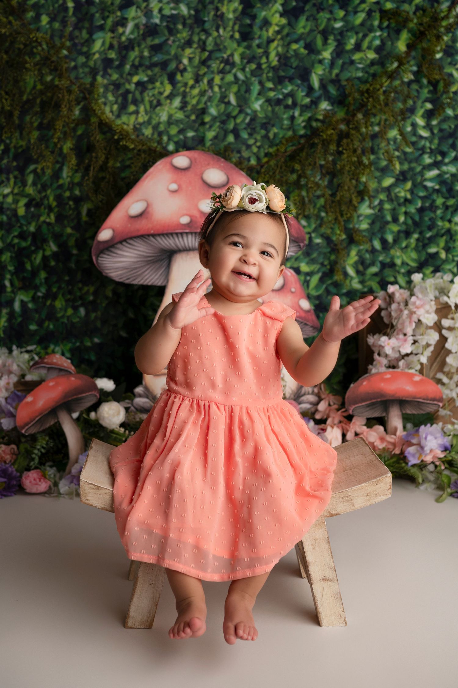 Whimsical coral dress and mushroom-themed photography setup with greenery backdrop.