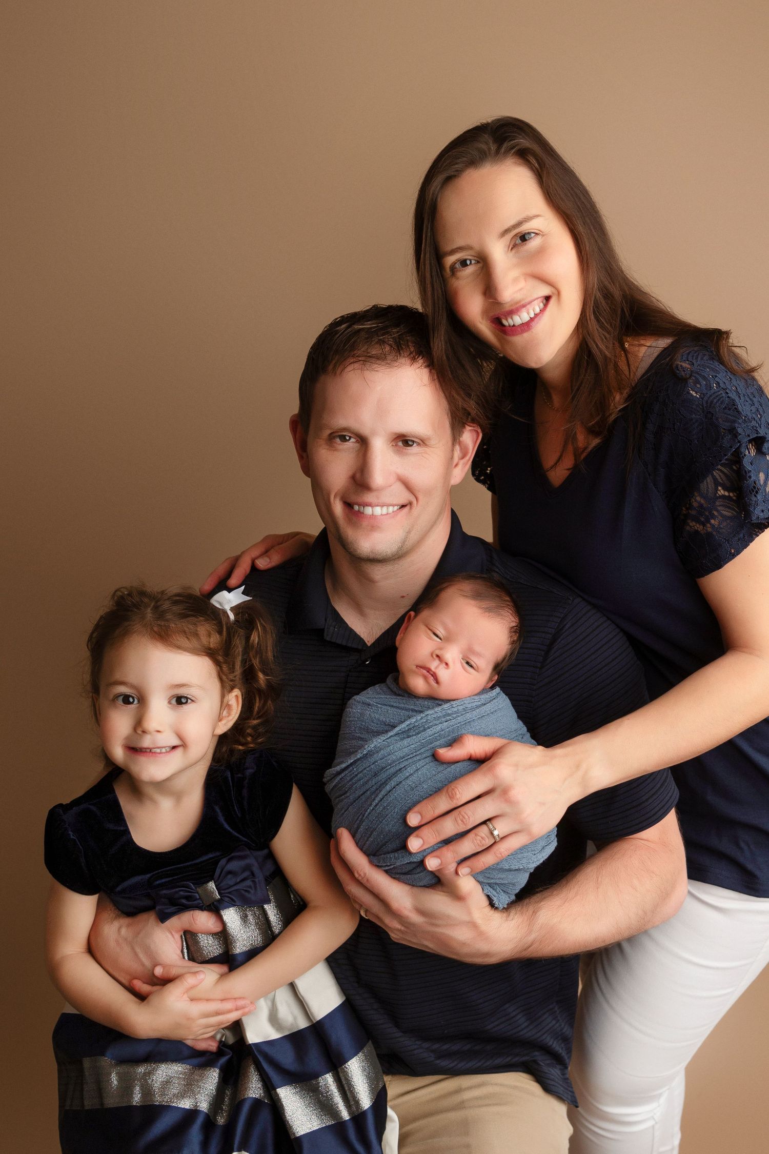 A family portrait series showing tender moments between parents and children against a warm brown backdrop.