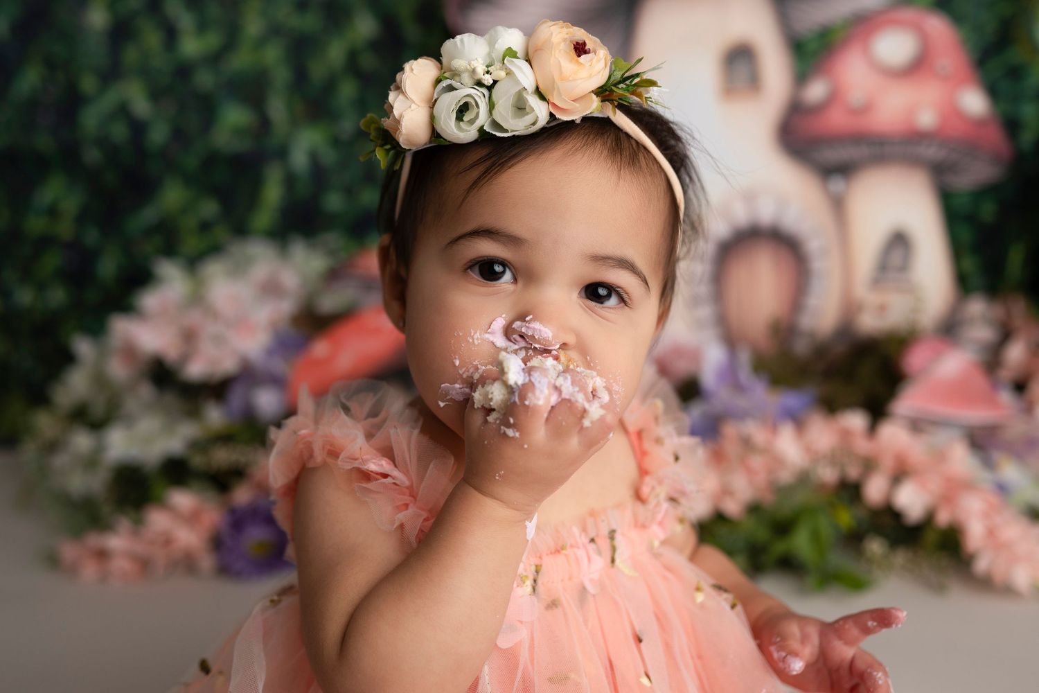 A series of photos showing a baby's first birthday cake smash session with a pink frosted cake and whimsical mushroom decor.