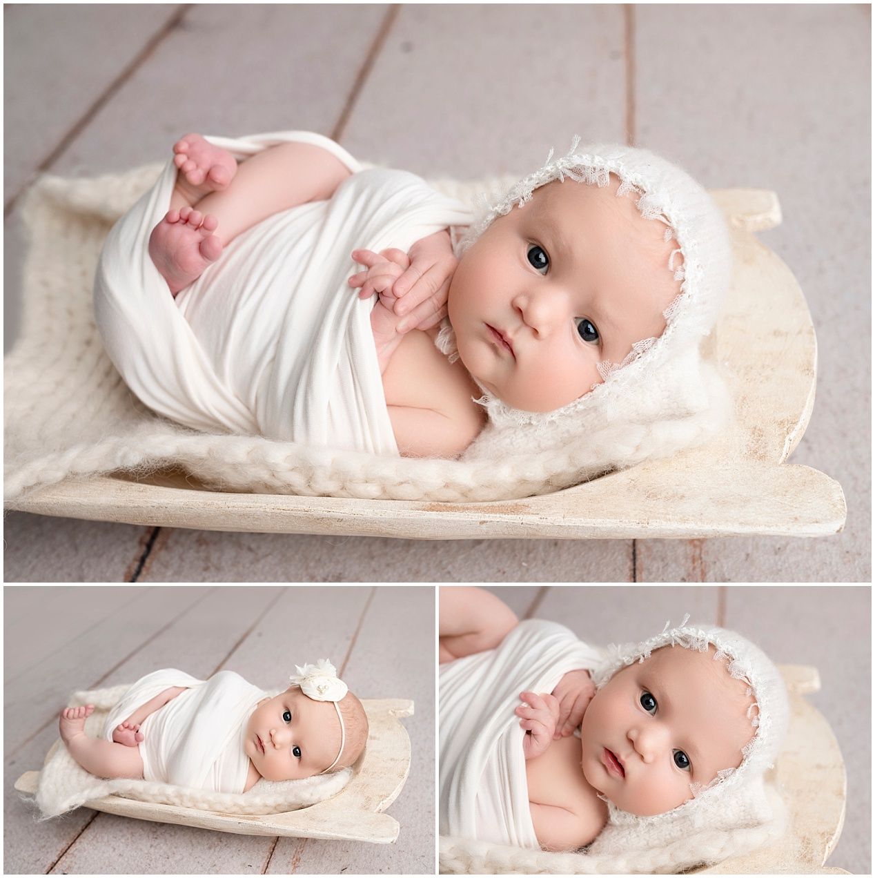 A newborn baby swaddled in soft white fabric lies on a cream colored blanket against wooden floor backdrop.
