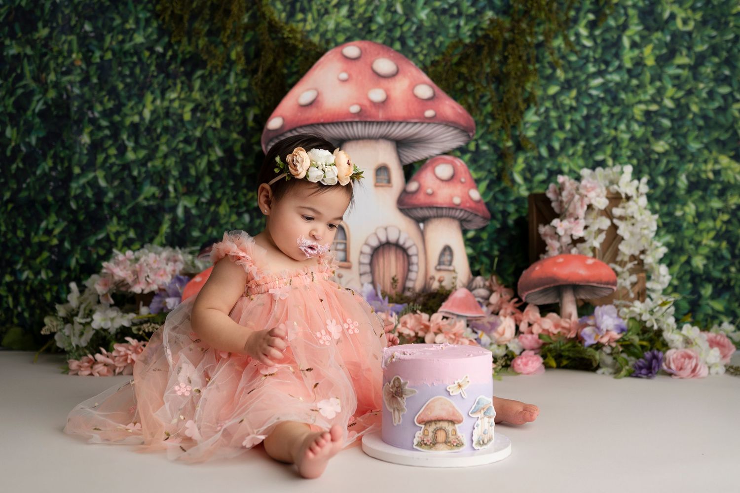 A fairy tale inspired photo scene with pink mushroom props and floral decorations against a garden backdrop.
