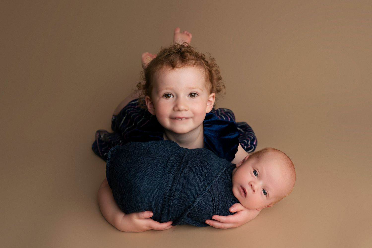 A collage of six professional studio portraits of a baby in navy blue outfits against a neutral beige background.