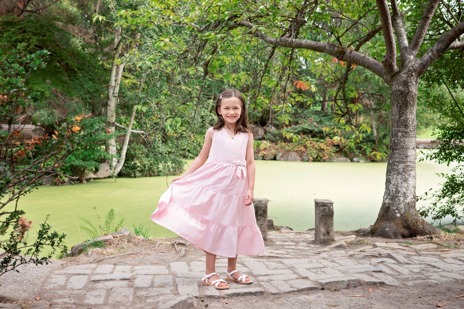 A series of connected photos shows someone in a pink dress walking along a stone path in a garden setting.