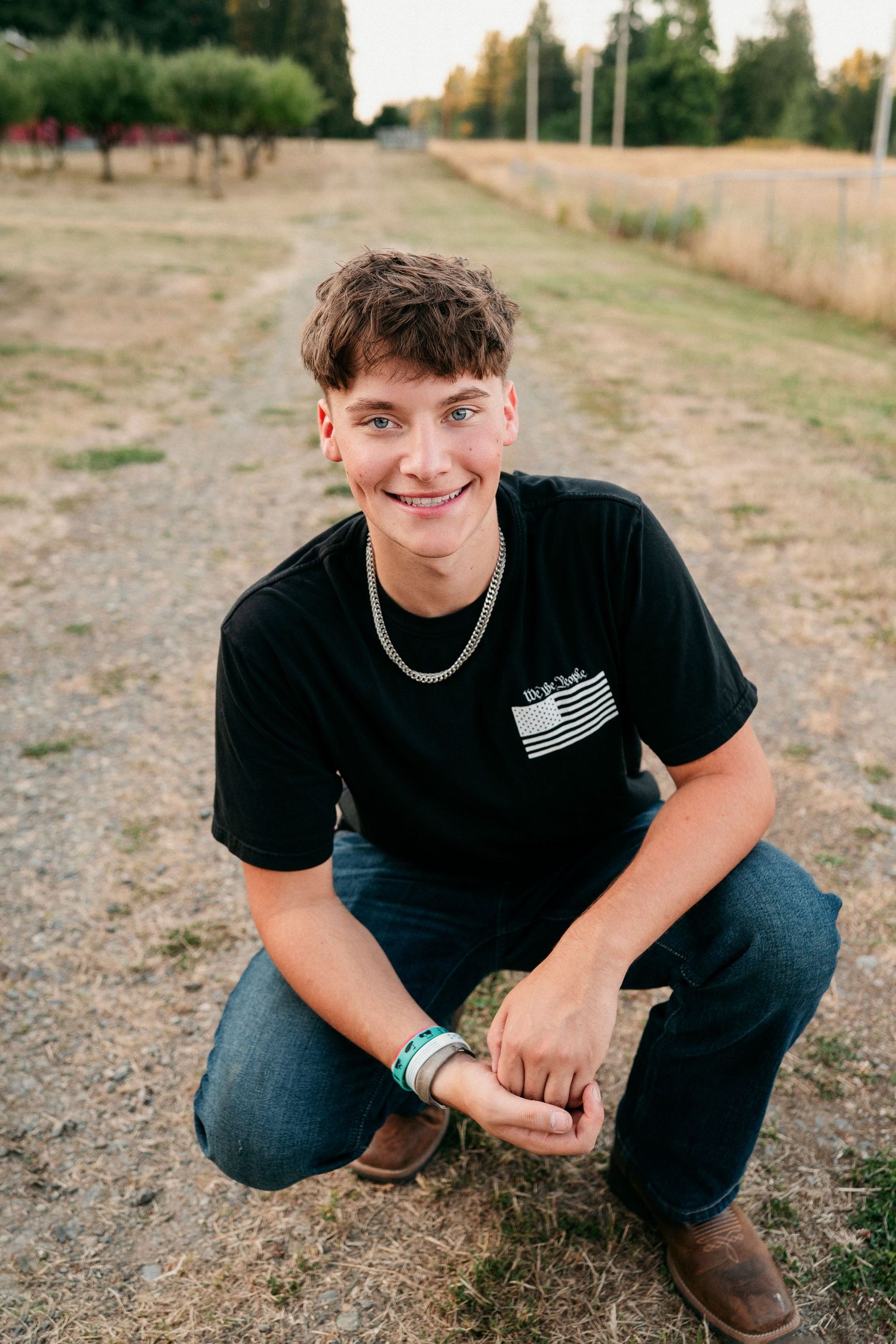 A person in a black t-shirt and jeans crouches outdoors on dry ground in a series of candid poses.
