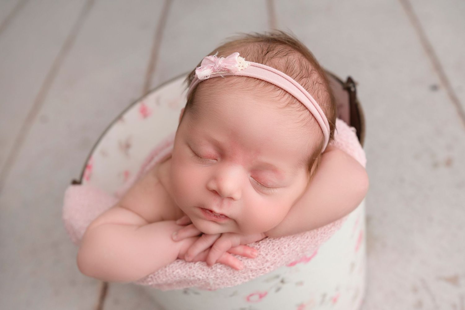 A sleeping newborn baby wearing pink clothing and headband is photographed in a collage of peaceful poses.