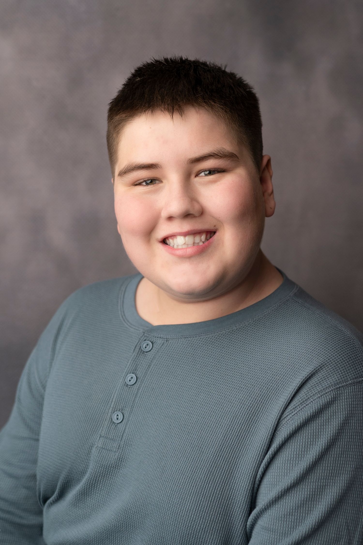 Series of studio portraits showing joyful expressions against a gray background wearing a blue-gray henley shirt.