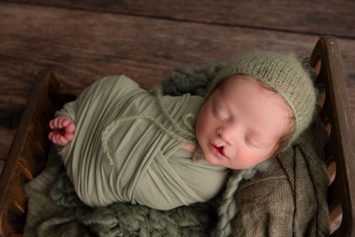 A series of connected photos showing a sleeping baby in a light green outfit resting on a wooden surface.