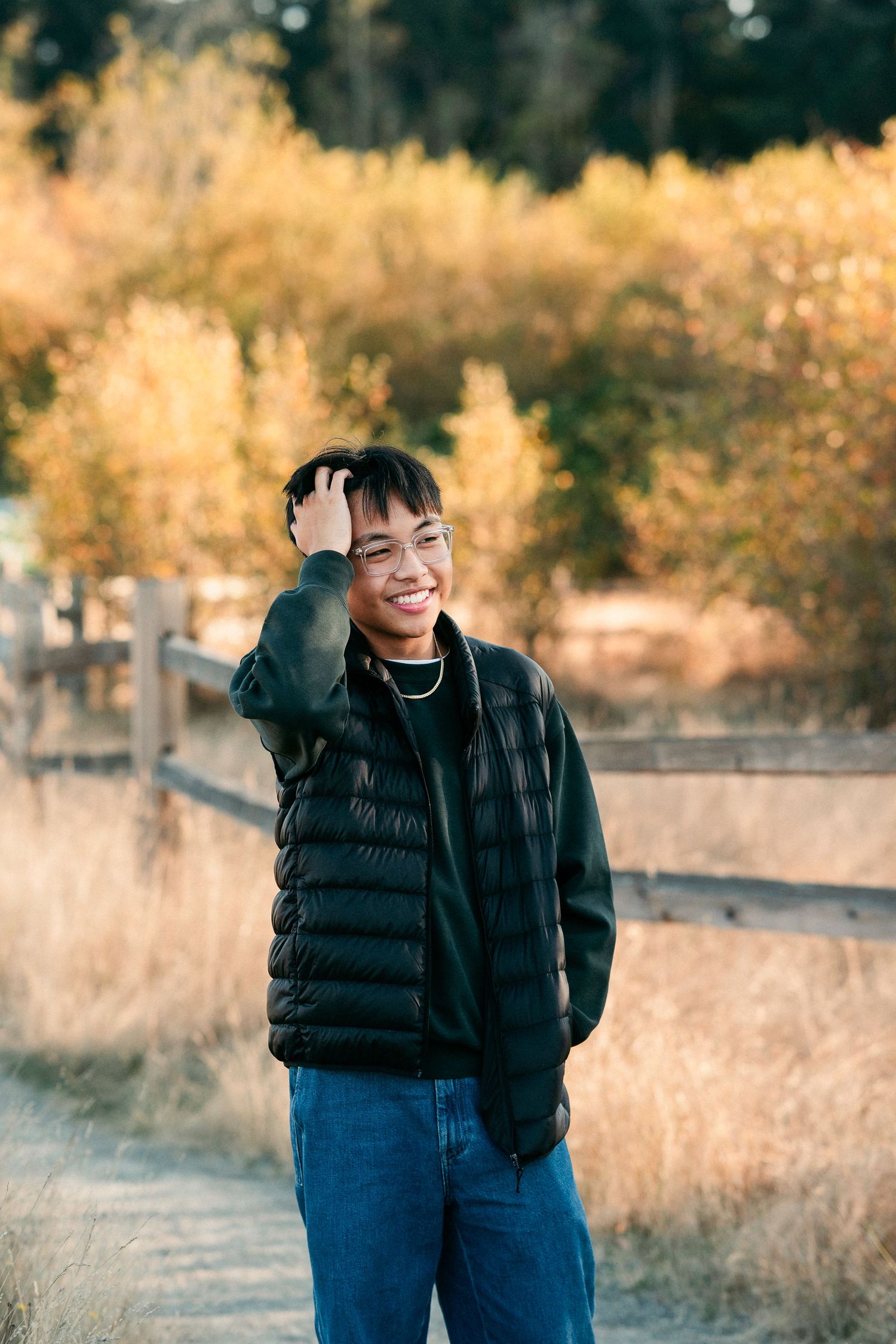 A person in a black puffer jacket stands in a golden field during autumn.