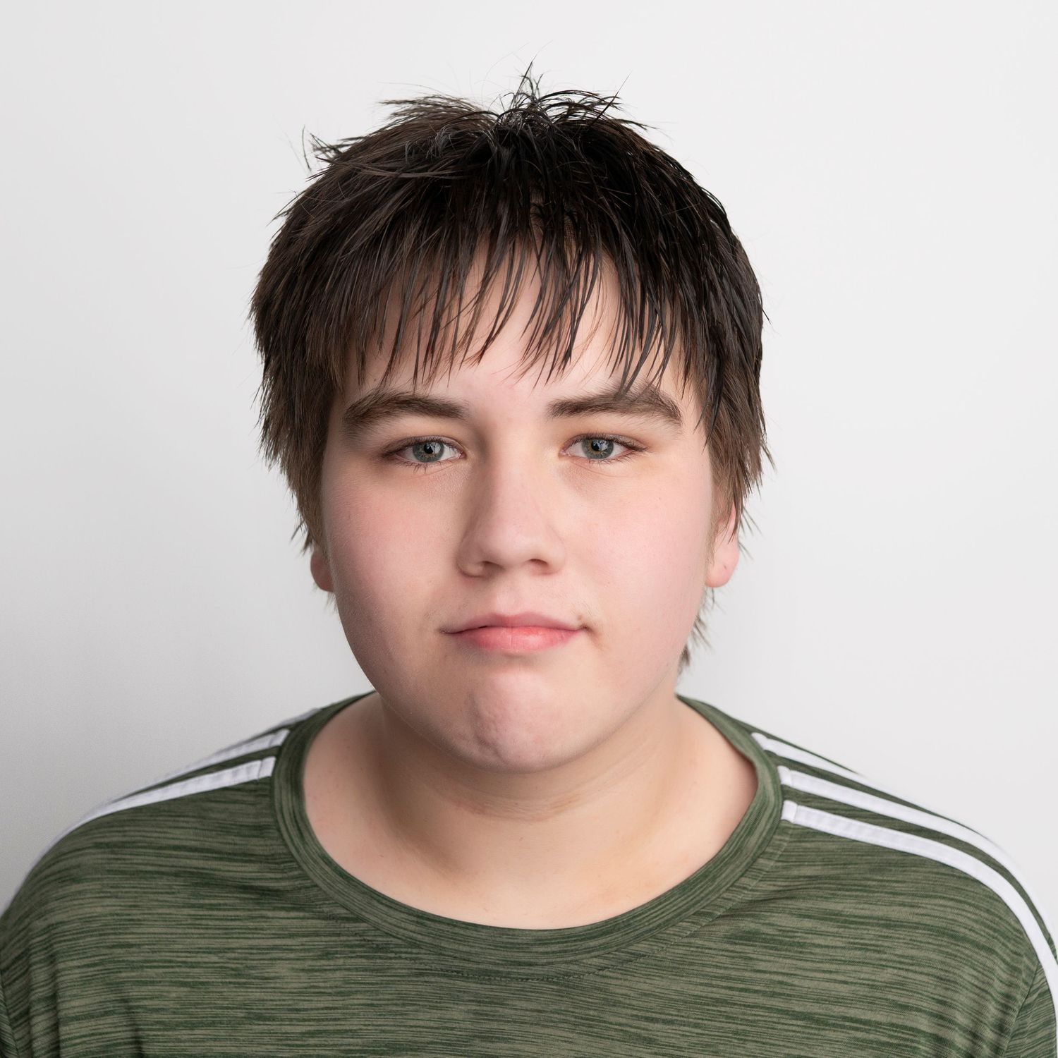 Person wearing a green shirt with white stripes on shoulders poses against a light background.