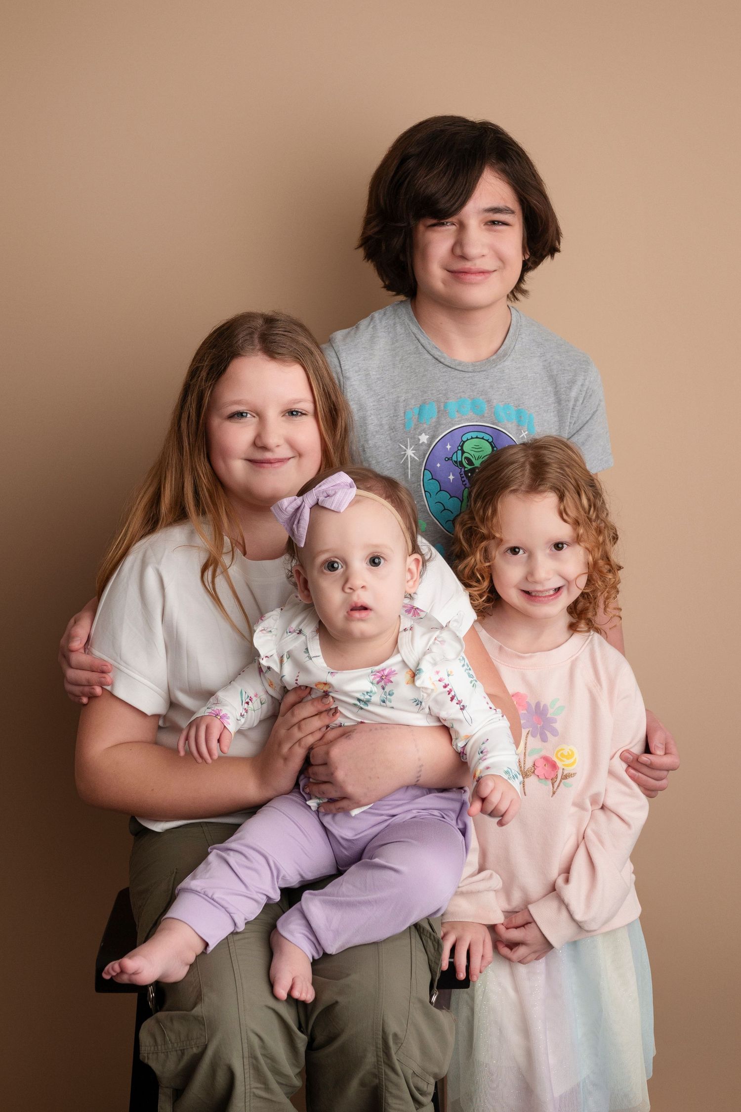 A series of studio portraits showing three siblings posing together with a baby in matching outfits against a beige backdrop.