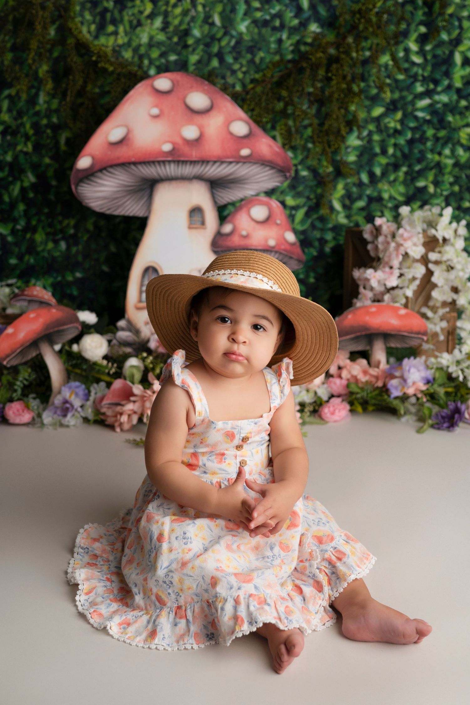 A whimsical woodland-themed photo setup with large decorative mushrooms and floral backdrop.